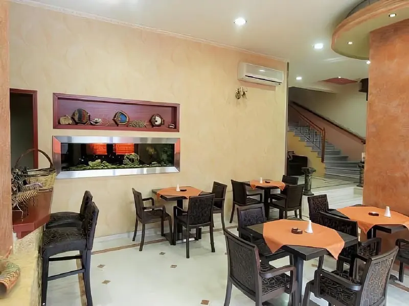Une salle de restaurant avec des tables et des chaises disposées sur un carrelage clair.