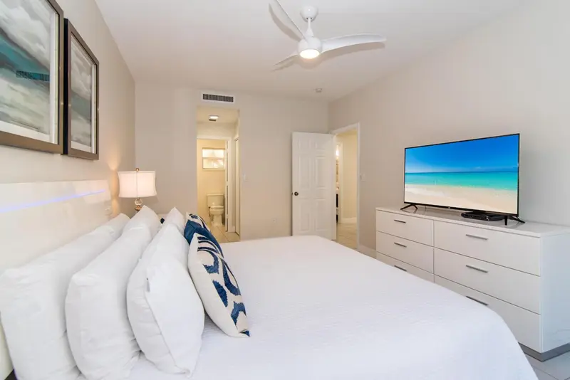 Une chambre lumineuse avec un grand lit recouvert de coussins blancs et une télévision à écran plat.