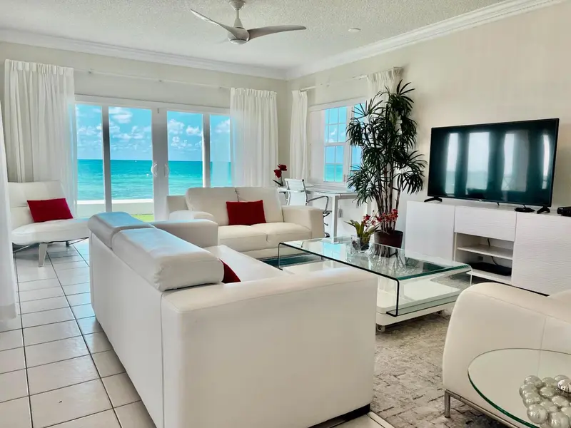 Espace de détente lumineux avec canapés blancs et vue sur la mer.