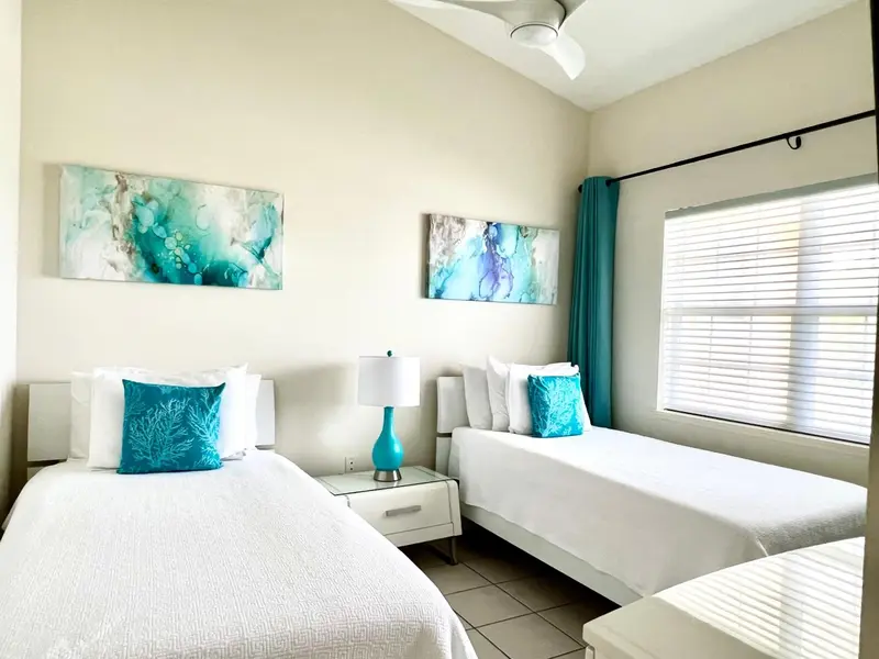 Une chambre lumineuse avec deux lits simples et une décoration turquoise.