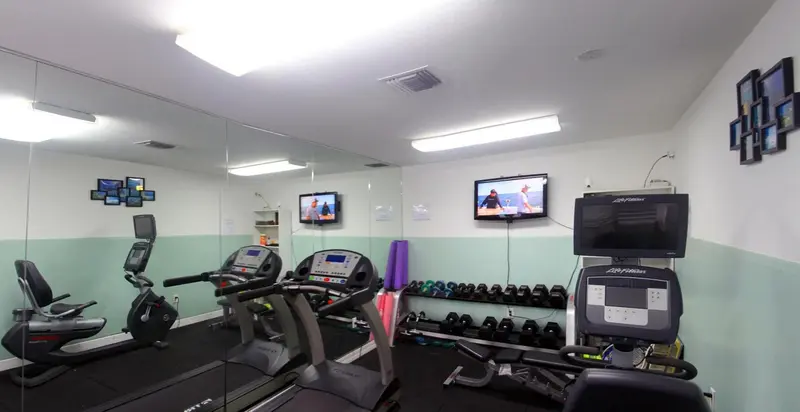 Une salle de sport lumineuse avec des équipements de fitness et des miroirs.