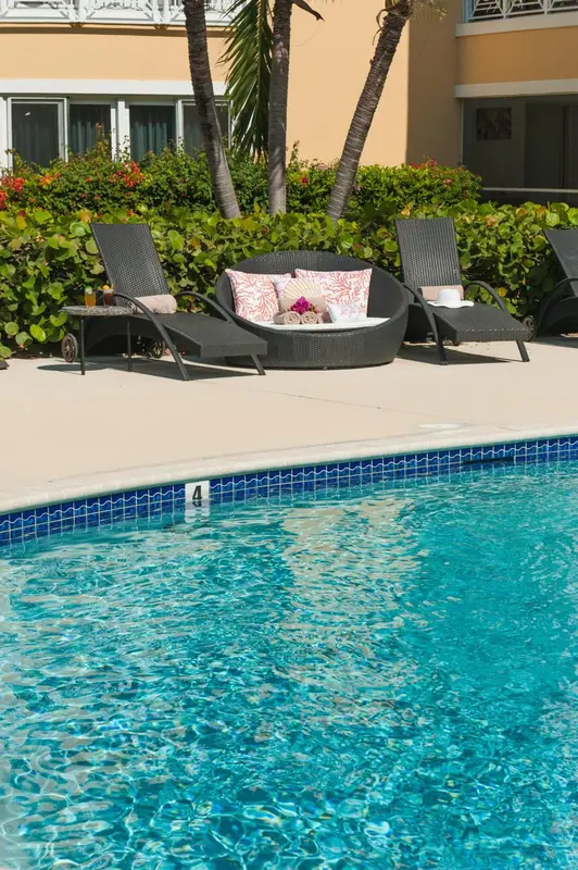 Transats et coussins disposés au bord d'une piscine turquoise.