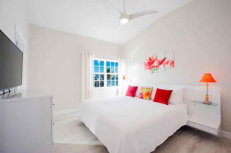 Une chambre lumineuse avec un lit recouvert de coussins rouges et une décoration florale.