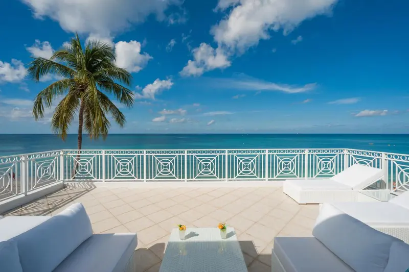 Terrasse ensoleillée avec mobilier blanc et vue sur la mer.