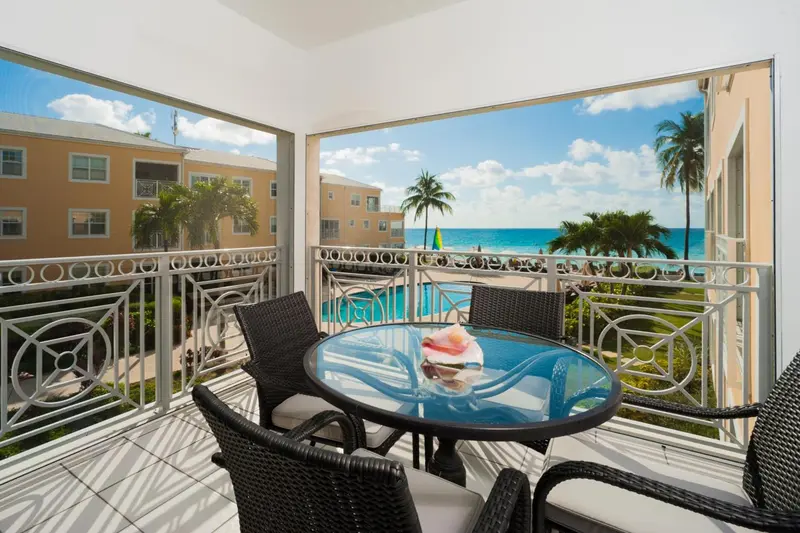 Terrasse avec table et chaises donnant sur une piscine et la mer.