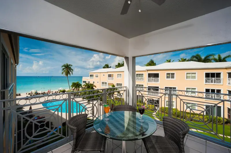 Une terrasse avec une table et des chaises offre une vue sur la mer et une piscine.
