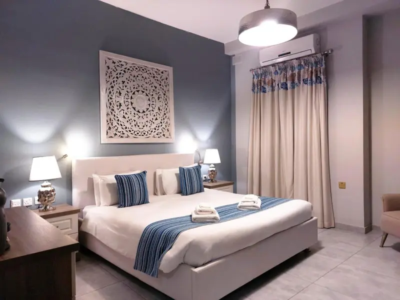 Une chambre lumineuse avec un grand lit recouvert d'une courtepointe bleue.