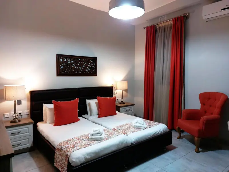 Une chambre avec un grand lit et un fauteuil rouge.