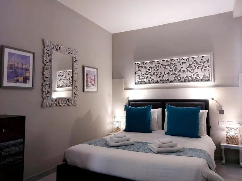 Une chambre avec un grand lit recouvert d'une courtepointe blanche et de coussins bleus.