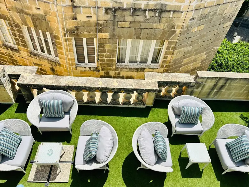 Espace de détente extérieur avec mobilier en osier et gazon artificiel.