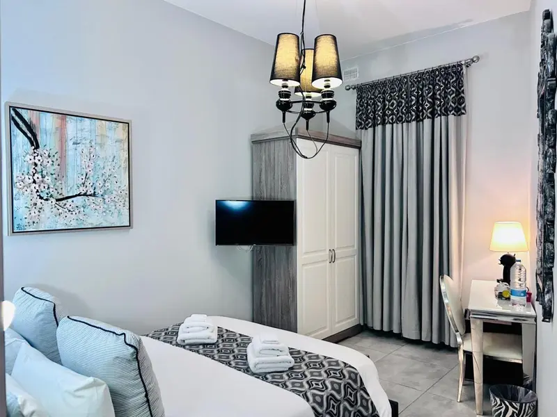 Une chambre lumineuse avec un lit recouvert d'une courtepointe blanche et d'oreillers.