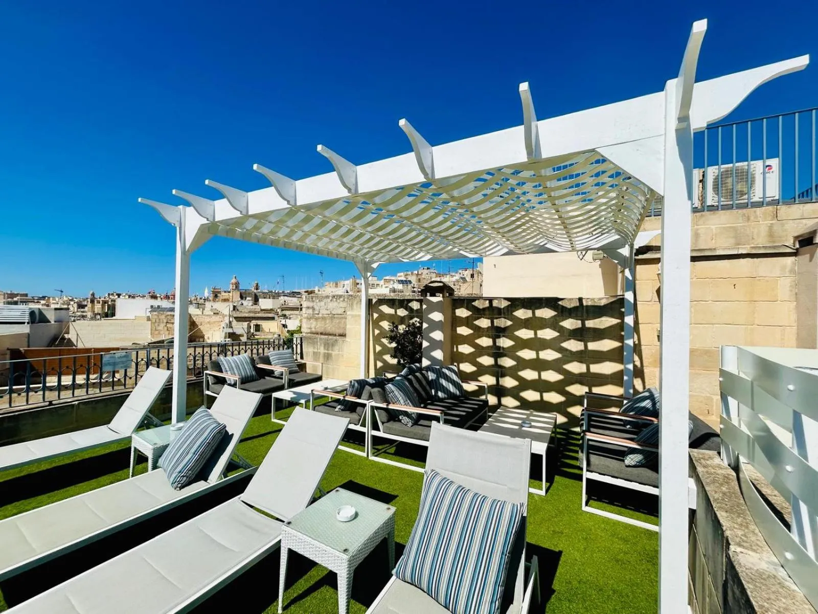 Terrasse aménagée avec des transats et une pergola ombragée offrant une vue sur la ville.