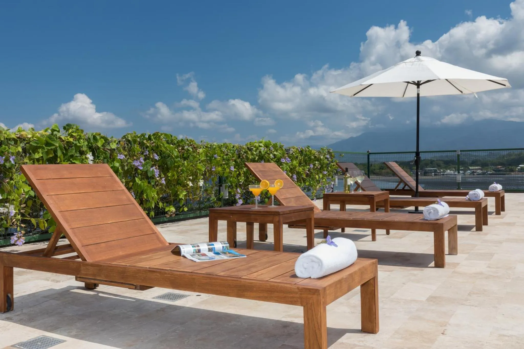 Transats en bois sur une terrasse ensoleillée avec des cocktails.