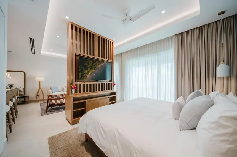 Une chambre lumineuse avec un grand lit et un espace salon.