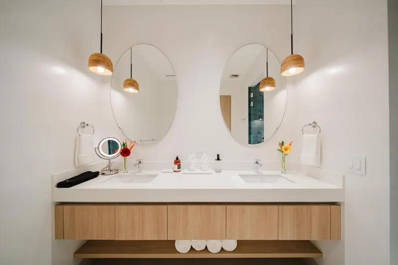 Une salle de bain lumineuse avec un grand miroir et un meuble vasque moderne.
