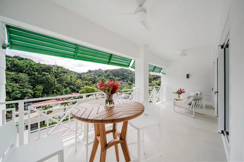 Terrasse avec table ronde en bois et vue sur la végétation.