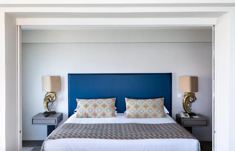 Une chambre avec un grand lit recouvert d'une courtepointe colorée et de coussins.