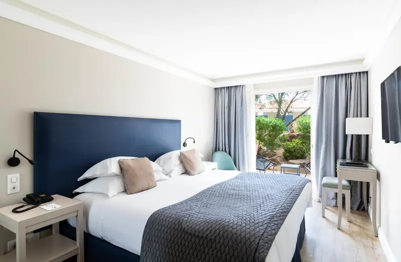 Une chambre lumineuse avec un grand lit et un accès à une terrasse.