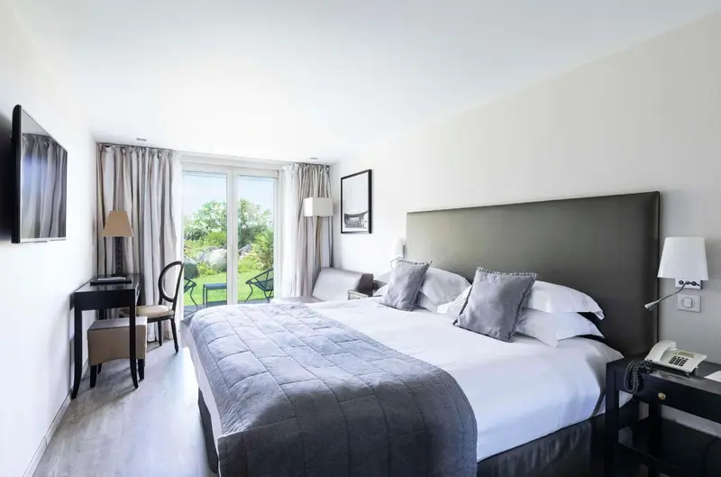 Une chambre lumineuse avec un grand lit et un accès à une terrasse.