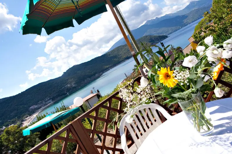 Une terrasse fleurie offre une vue sur la mer et les montagnes.
