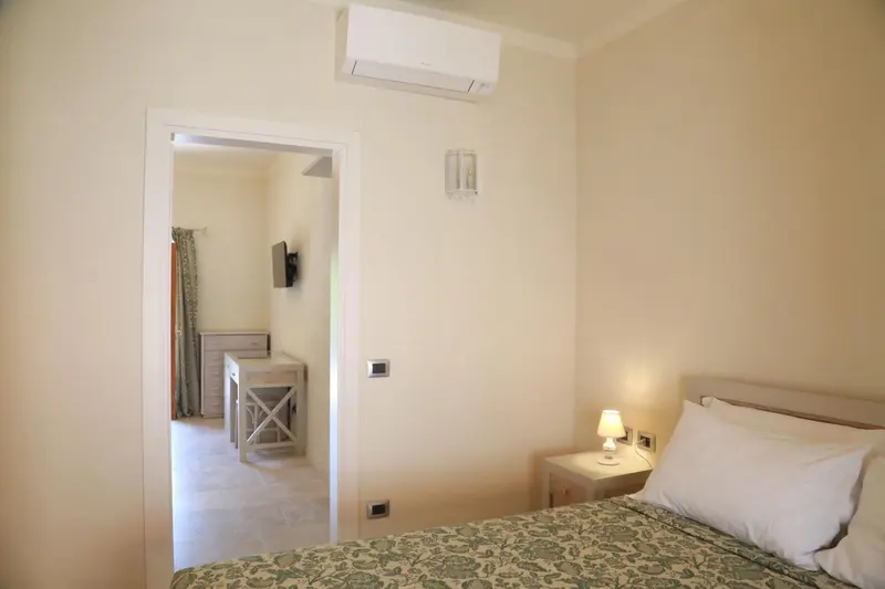 Une chambre lumineuse avec un lit et un accès vers un espace salon.