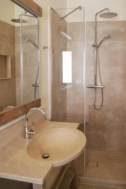 Une douche à l'italienne avec un lavabo intégré dans un décor beige.