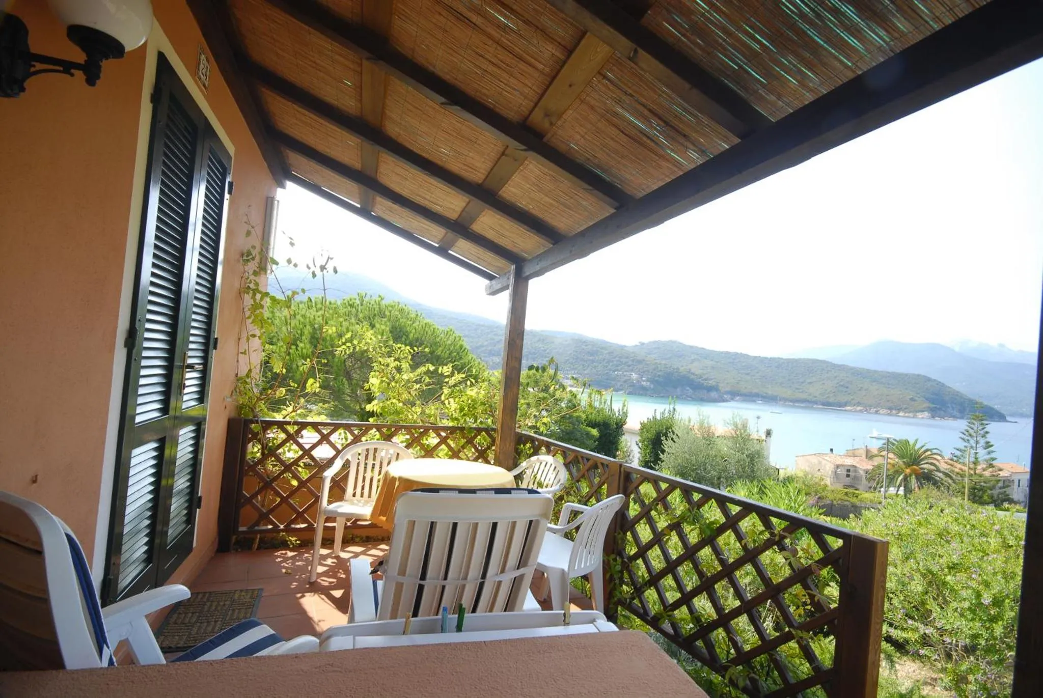 Terrasse ombragée avec mobilier de jardin et vue sur la mer.