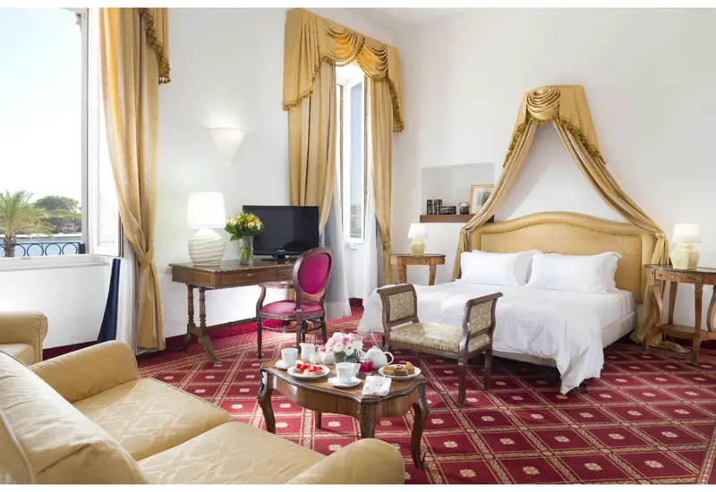 Chambre lumineuse avec un lit à baldaquin et un coin salon.