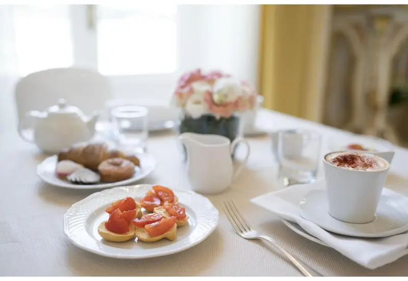 Une table est dressée avec des viennoiseries, des fruits et des boissons.