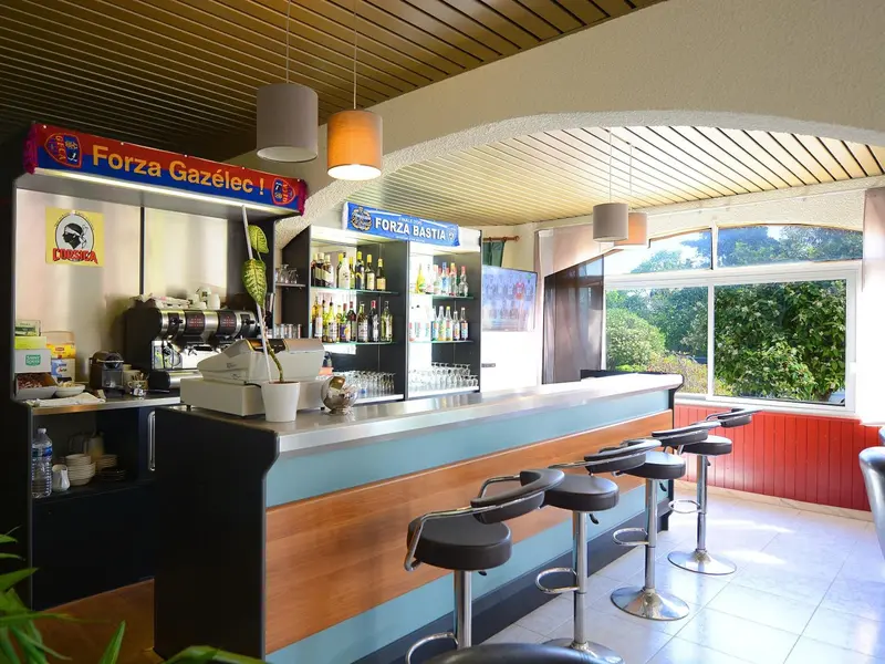 Un comptoir de bar avec des bouteilles et des tabourets hauts.