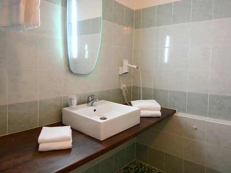 Une salle de bain moderne avec lavabo et serviettes.
