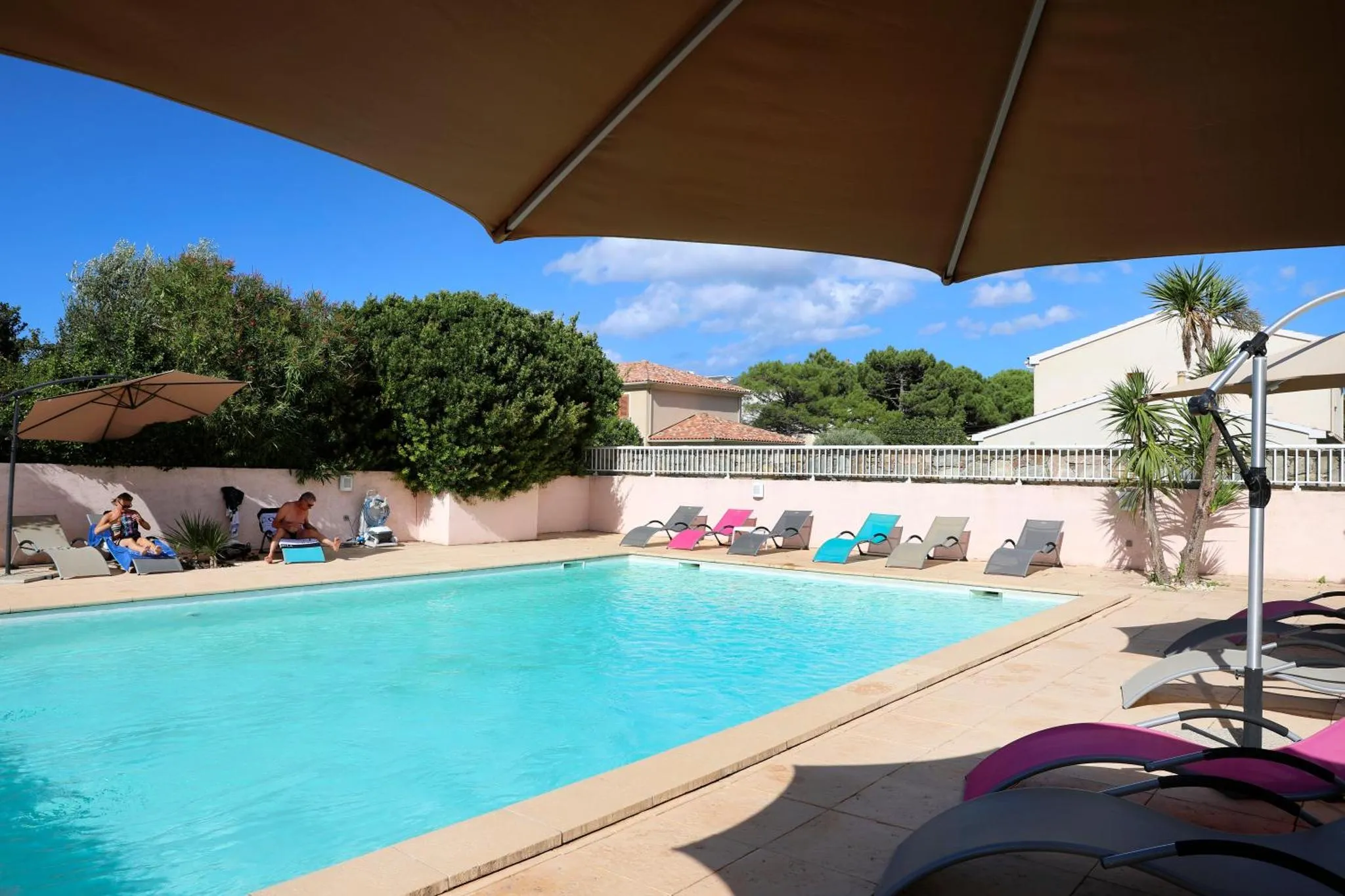 Transats colorés disposés autour d'une piscine ensoleillée.