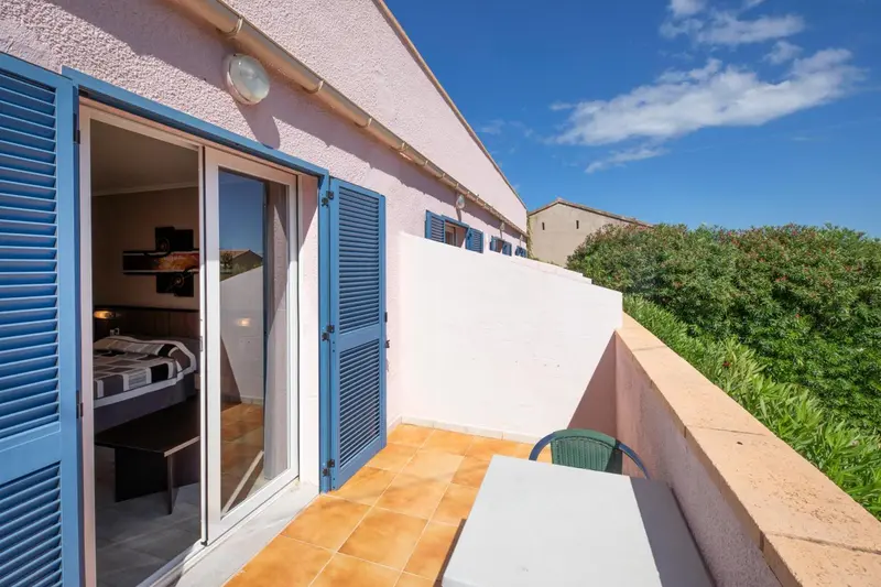 Une terrasse carrelée s'ouvre sur une chambre lumineuse.