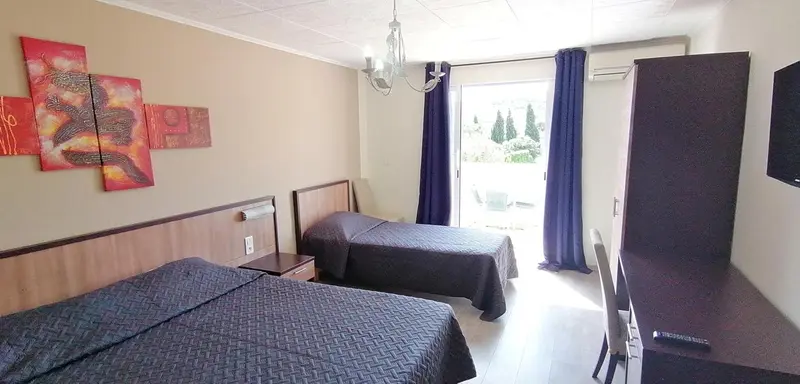 Une chambre avec deux lits et un accès à une terrasse.