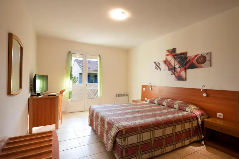 Une chambre lumineuse avec un lit recouvert d'une couverture à carreaux.