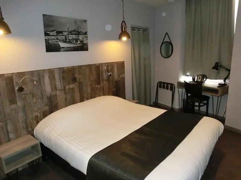 Une chambre lumineuse avec un grand lit et un bureau.