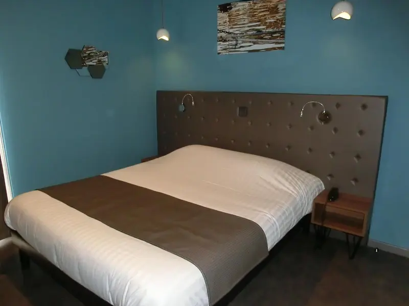 Une chambre avec un grand lit recouvert d'une courtepointe blanche et grise.