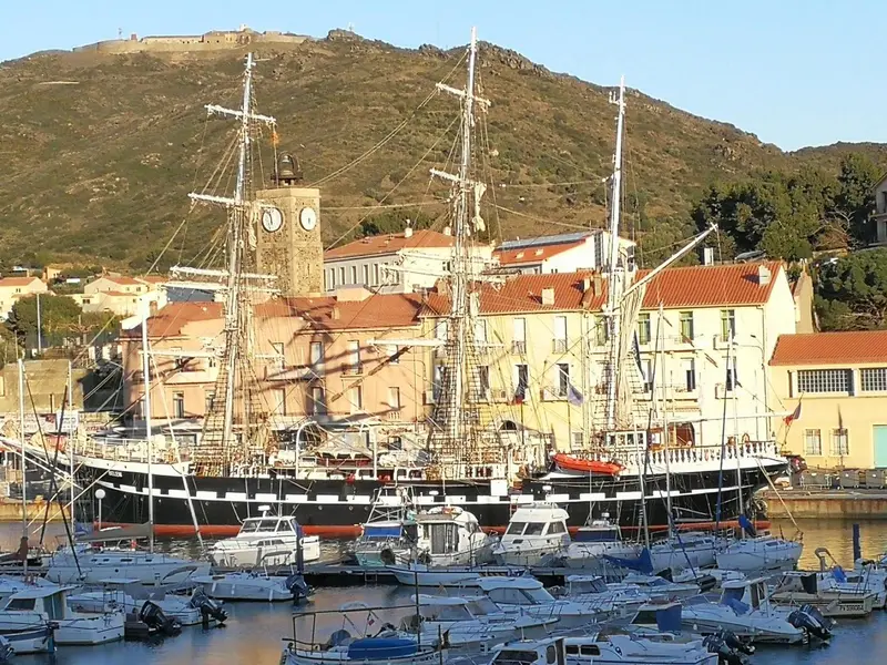 Un grand voilier amarré dans un port de ville côtière ensoleillé.
