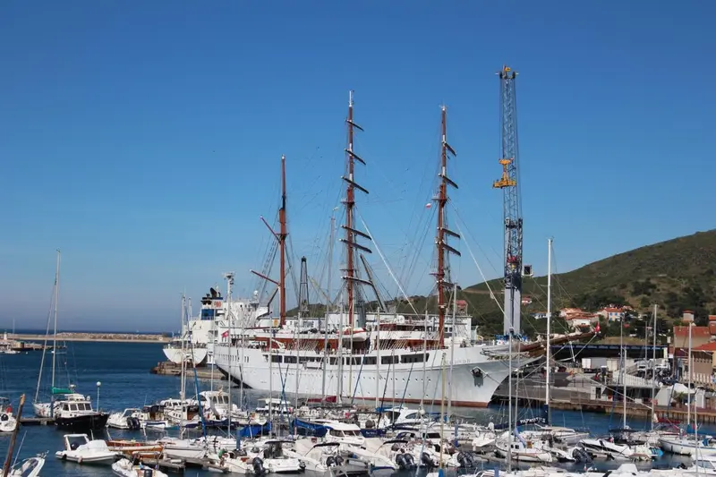 Un grand voilier amarré dans un port de plaisance ensoleillé.