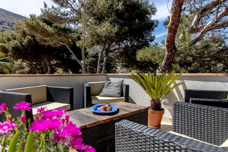 Salon de jardin avec mobilier en rotin et plantes fleuries sur une terrasse.