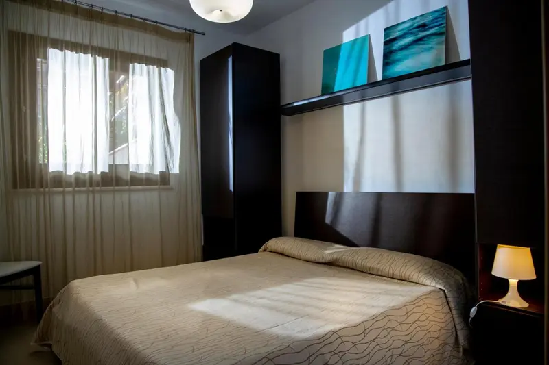Une chambre lumineuse avec un grand lit et un placard.