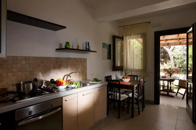 Une cuisine lumineuse s'ouvre sur une table à manger et une terrasse.