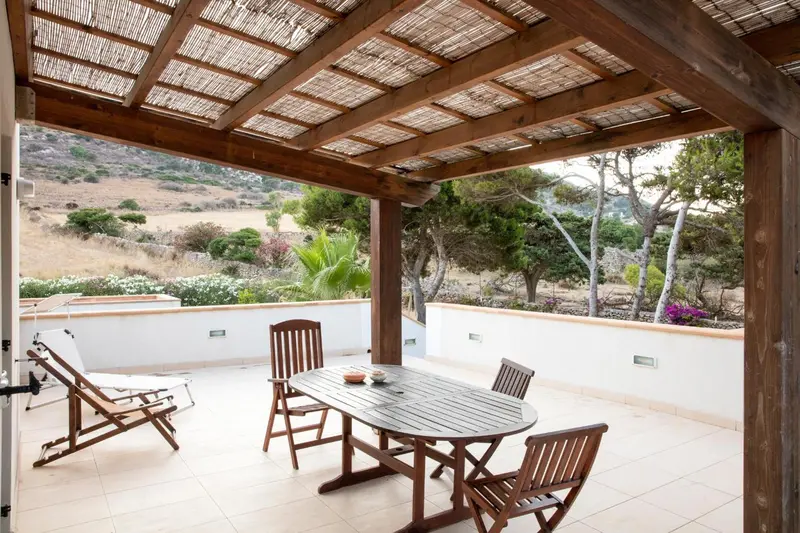 Terrasse ombragée avec mobilier de jardin et vue sur la végétation.