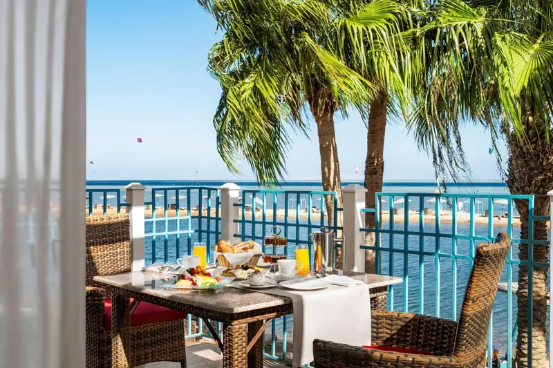 Une table de petit-déjeuner est dressée sur une terrasse avec vue sur la mer.