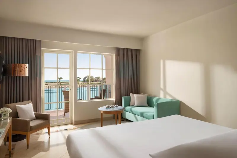 Une chambre lumineuse avec un coin salon et une vue sur la mer.