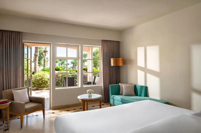 Une chambre lumineuse s'ouvre sur une terrasse avec vue sur la végétation.