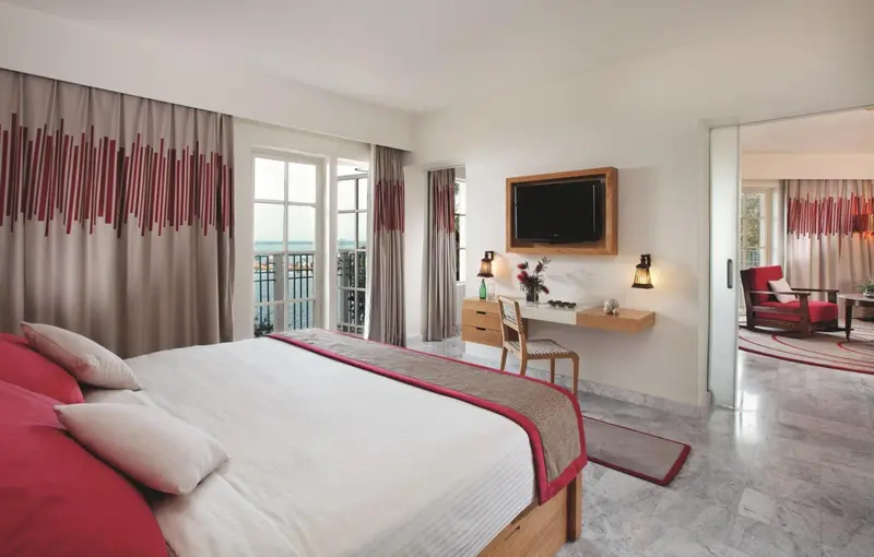 Une chambre lumineuse avec un grand lit et un bureau près d'une fenêtre.