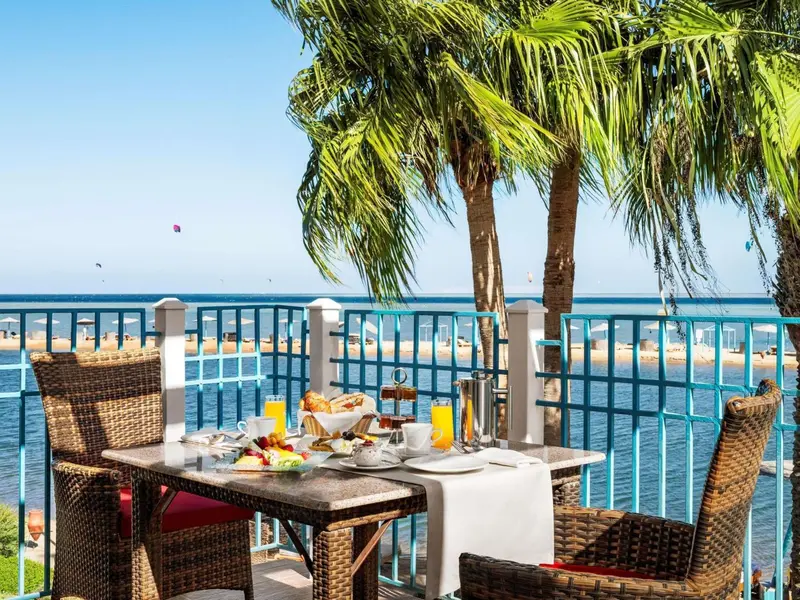 Une table de petit-déjeuner est dressée sur une terrasse avec vue sur la mer.