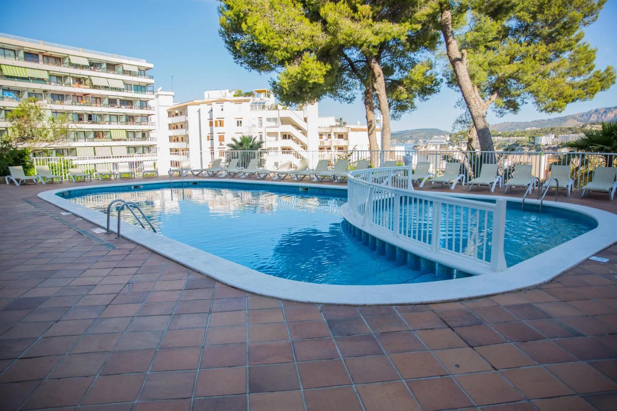 Une piscine rectangulaire avec des transats et des parasols sur une terrasse carree.