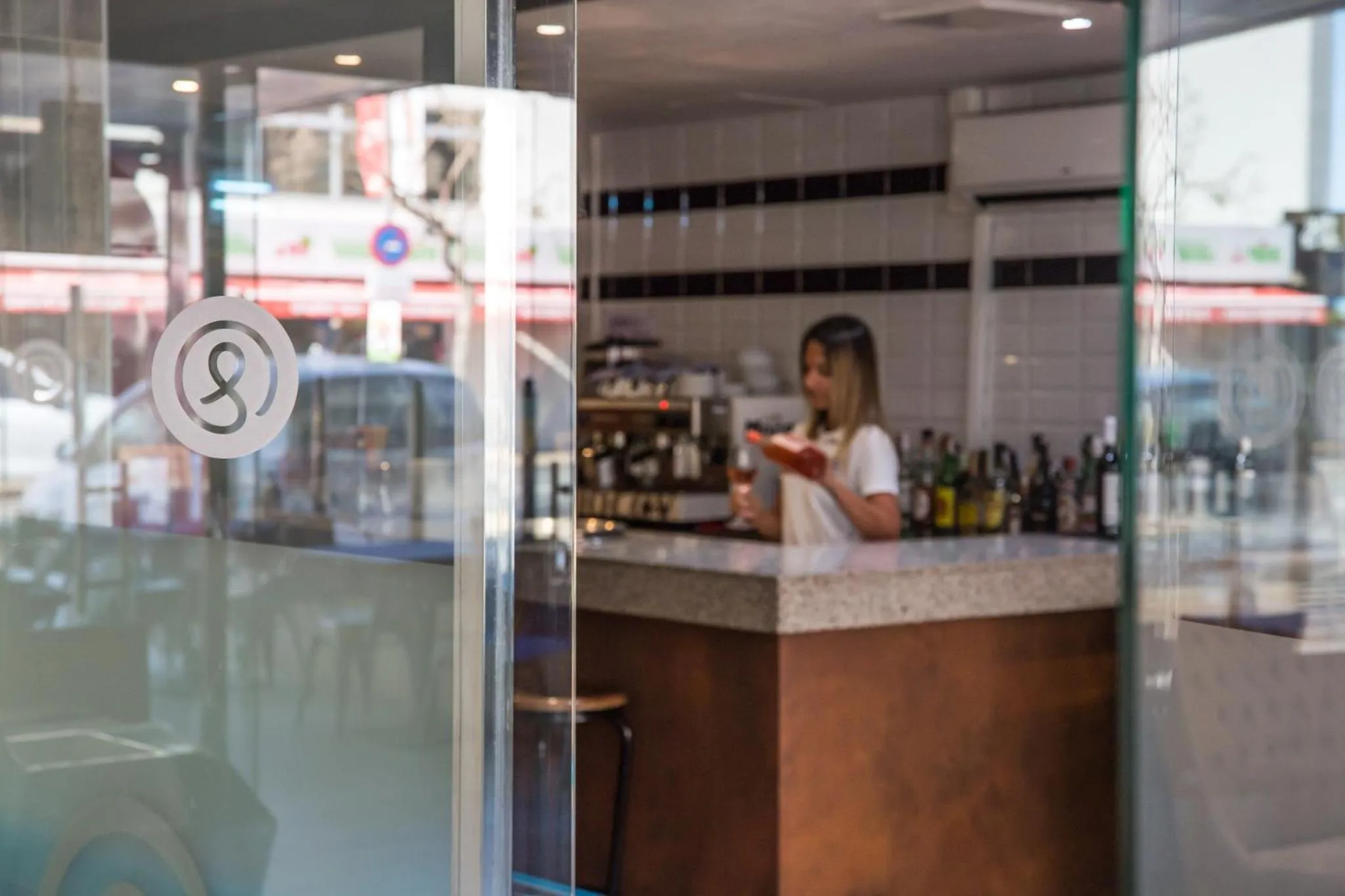 Une personne travaille derrière un comptoir de bar bien garni.
